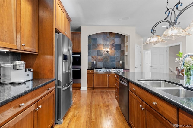 6040 Virgil St, Arvada, CO 80403 - kitchen with appliances with stainless steel finishes, a sink, brown cabinetry, light wood-type flooring, and backsplash
