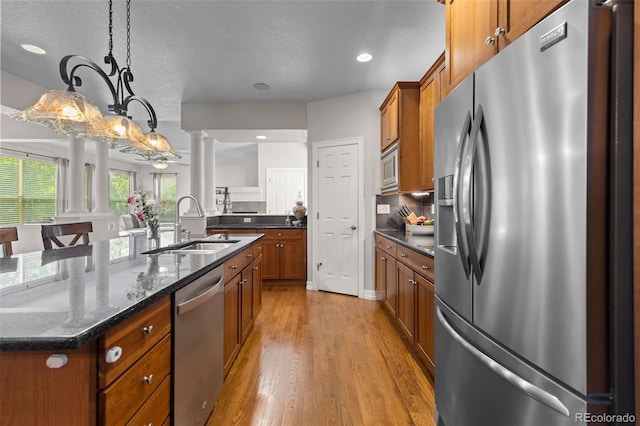 6040 Virgil St, Arvada, CO 80403 - kitchen featuring appliances with stainless steel finishes, ornate columns, a sink, brown cabinets, and a textured ceiling
