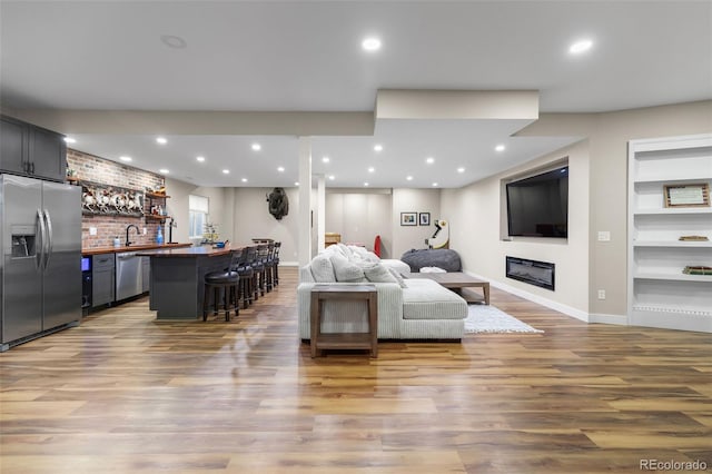 6040 Virgil St, Arvada, CO 80403 - living room with bar with sink, wood finished floors, baseboards, recessed lighting, and a glass covered fireplace