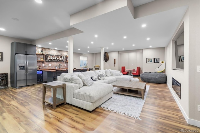 6040 Virgil St, Arvada, CO 80403 - living room featuring bar with sink, light wood-style floors, recessed lighting, baseboards, and a glass covered fireplace