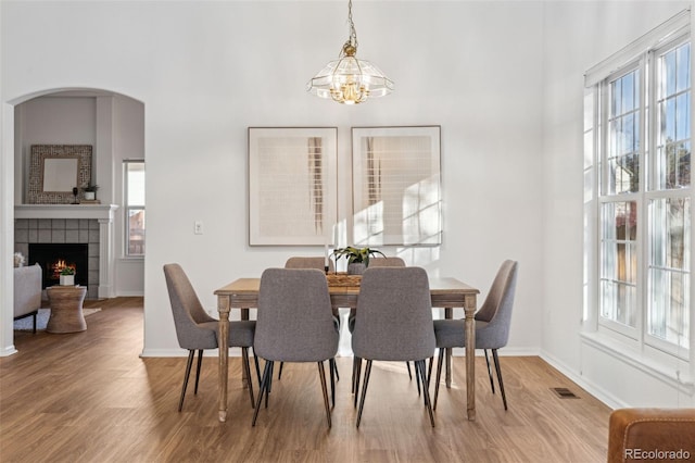 dining space featuring an inviting chandelier, a fireplace, and light hardwood / wood-style flooring