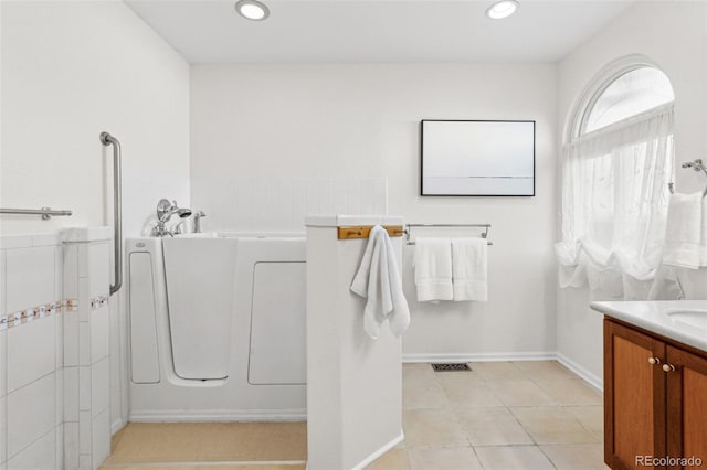 bathroom featuring vanity, a washtub, and tile patterned floors