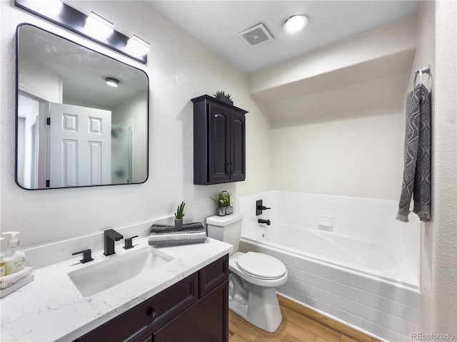 bathroom featuring hardwood / wood-style flooring, vanity, tiled bath, and toilet