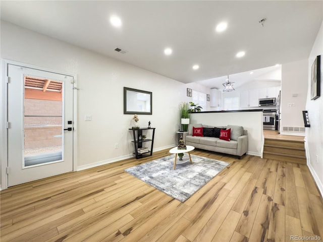 living room with light hardwood / wood-style flooring and vaulted ceiling