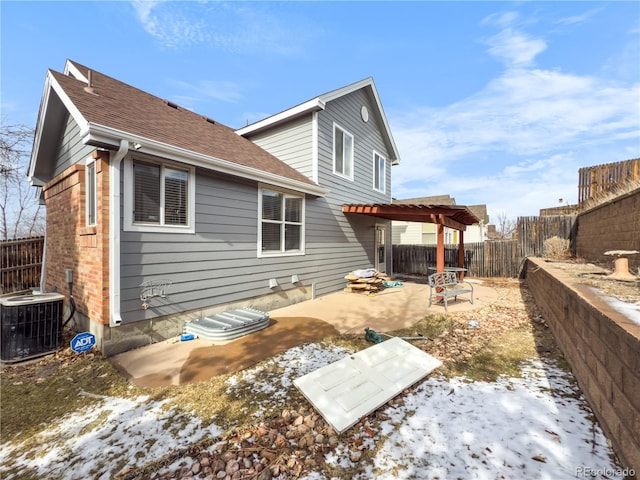 snow covered rear of property featuring cooling unit, a pergola, and a patio