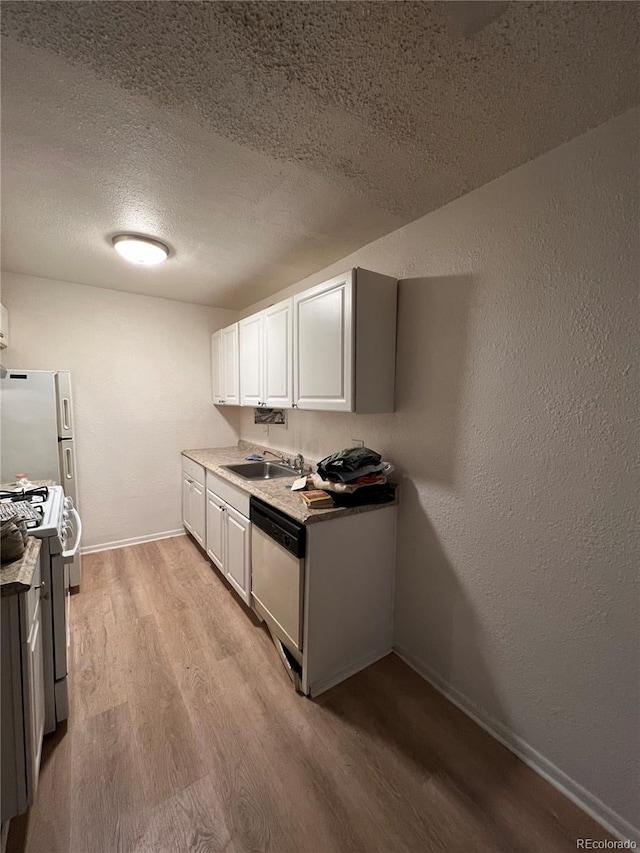 kitchen with light hardwood / wood-style floors, white cabinetry, sink, white appliances, and a textured ceiling