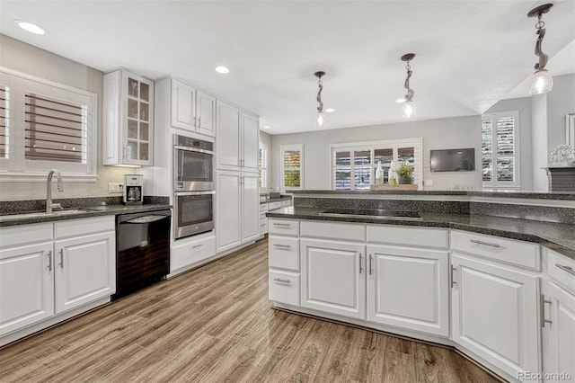 kitchen with light hardwood / wood-style floors, black appliances, sink, pendant lighting, and white cabinetry