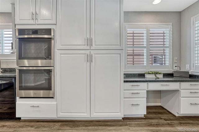 kitchen with dark wood-type flooring, white cabinetry, double oven, and dishwasher