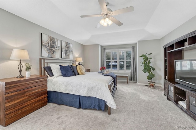 carpeted bedroom featuring ceiling fan and a raised ceiling