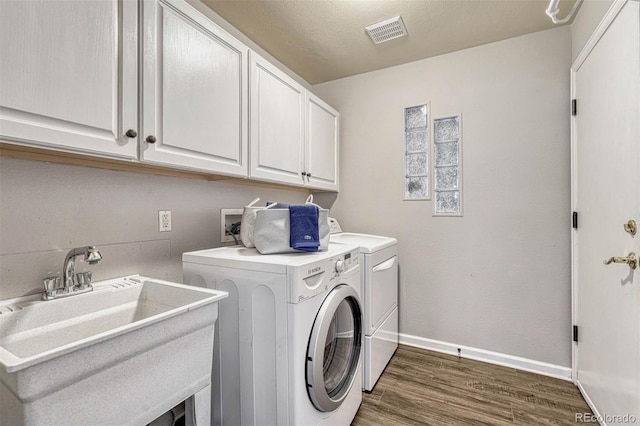 washroom with dark hardwood / wood-style flooring, cabinets, a textured ceiling, sink, and independent washer and dryer