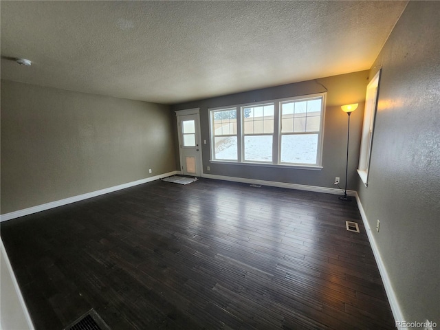 spare room featuring dark wood-type flooring and a textured ceiling