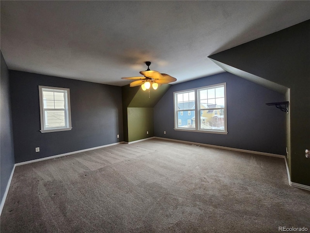 additional living space with vaulted ceiling, plenty of natural light, carpet flooring, and ceiling fan