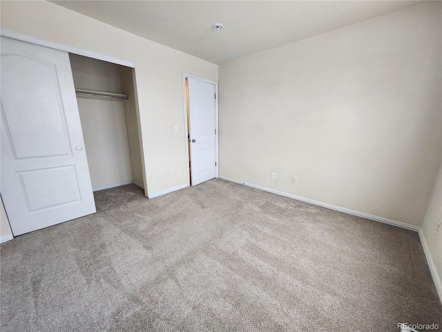 unfurnished bedroom featuring light colored carpet and a closet