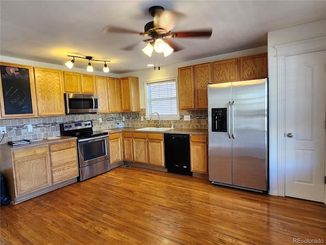 kitchen featuring stainless steel appliances, light wood-type flooring, a sink, and backsplash