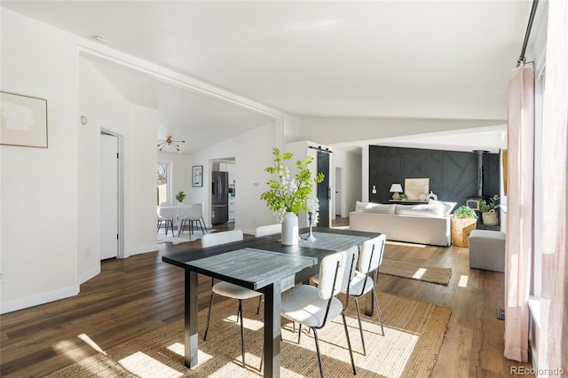 dining room featuring lofted ceiling, dark hardwood / wood-style flooring, a barn door, and ceiling fan