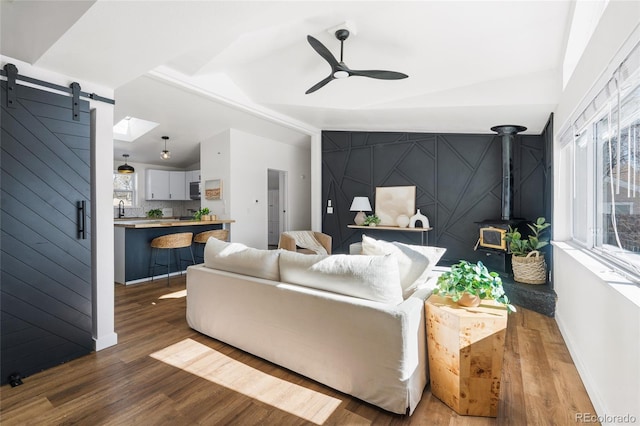 living room featuring lofted ceiling, sink, ceiling fan, dark hardwood / wood-style floors, and a barn door