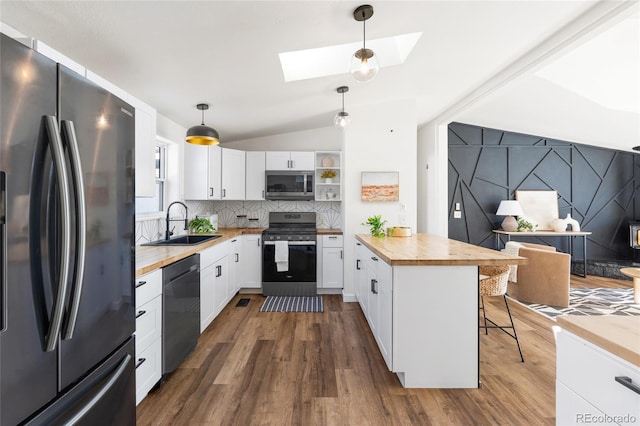 kitchen with white cabinetry, hanging light fixtures, butcher block countertops, and appliances with stainless steel finishes