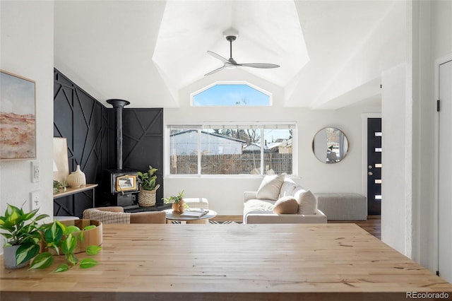 interior space featuring vaulted ceiling, a wood stove, hardwood / wood-style floors, and ceiling fan