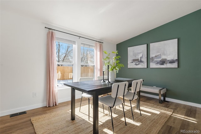 dining space with hardwood / wood-style floors and vaulted ceiling