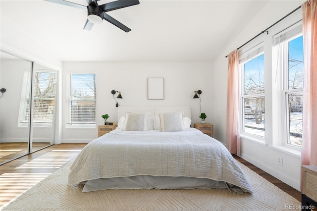 bedroom featuring ceiling fan, hardwood / wood-style floors, and multiple windows