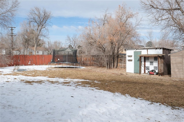 yard layered in snow with a trampoline and a storage unit