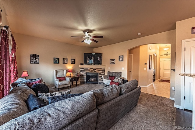 12420 Mount Belford Way, Peyton, CO 80831 - living room featuring arched walkways, a ceiling fan, a stone fireplace, and baseboards