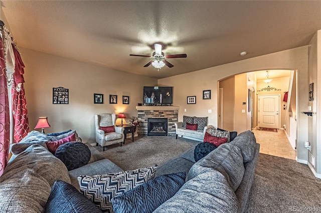 12420 Mount Belford Way, Peyton, CO 80831 - living room featuring arched walkways, ceiling fan, carpet floors, a stone fireplace, and baseboards