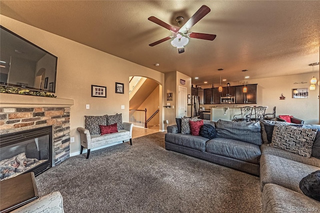 12420 Mount Belford Way, Peyton, CO 80831 - living area with a ceiling fan, arched walkways, carpet, a fireplace, and a textured ceiling