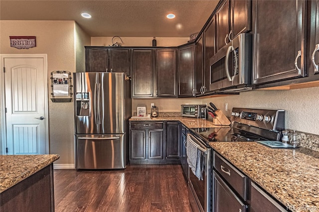 12420 Mount Belford Way, Peyton, CO 80831 - kitchen featuring stainless steel appliances, a textured wall, stone countertops, dark brown cabinetry, and dark wood-style floors