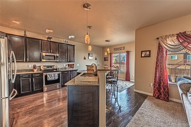 12420 Mount Belford Way, Peyton, CO 80831 - kitchen featuring stainless steel appliances, a sink, a textured ceiling, a breakfast bar area, and dark wood-style floors