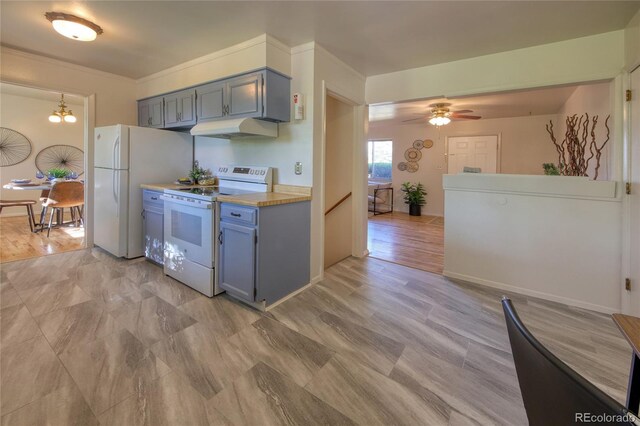 1227 Holmes Dr, Colorado Springs, CO 80909 - kitchen with white appliances, under cabinet range hood, light countertops, ceiling fan, and blue cabinetry