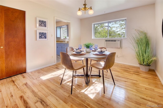 1227 Holmes Dr, Colorado Springs, CO 80909 - dining space with a wall mounted AC, a chandelier, light wood-type flooring, and baseboards