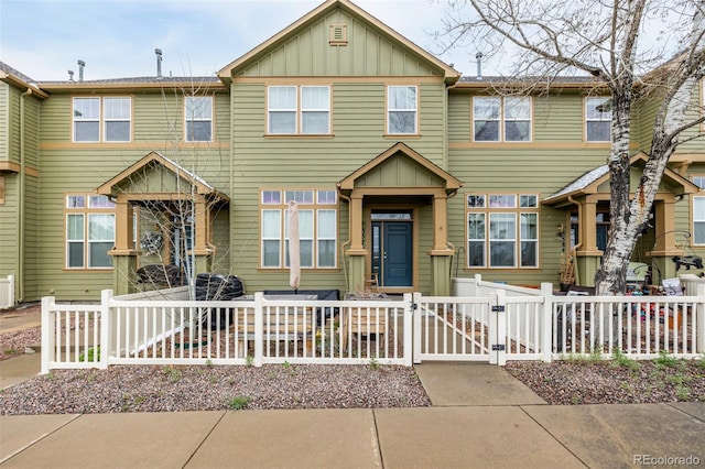 townhome / multi-family property featuring board and batten siding, a fenced front yard, and a gate