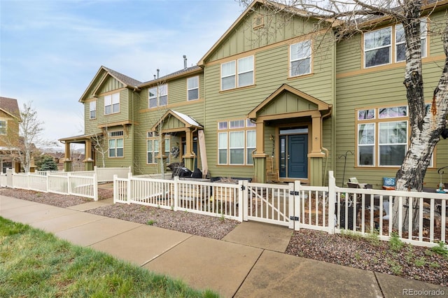 townhome / multi-family property with board and batten siding, a fenced front yard, and a gate