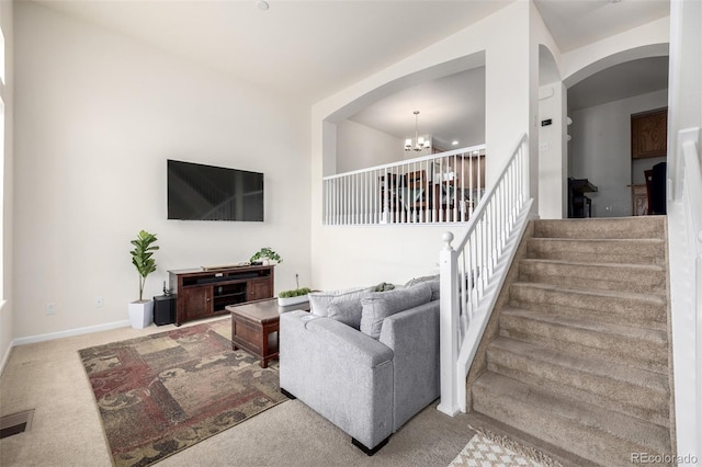 carpeted living area with baseboards, an inviting chandelier, visible vents, stairs, and arched walkways