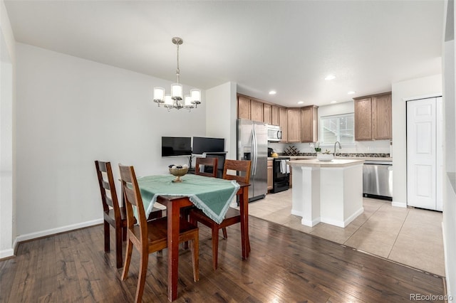 dining room with light wood finished floors, a chandelier, baseboards, and recessed lighting
