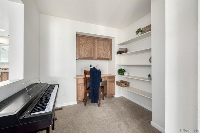 office area featuring built in desk, carpet flooring, and baseboards