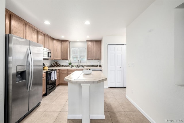 kitchen with a sink, stainless steel appliances, baseboards, light tile patterned floors, and a kitchen island