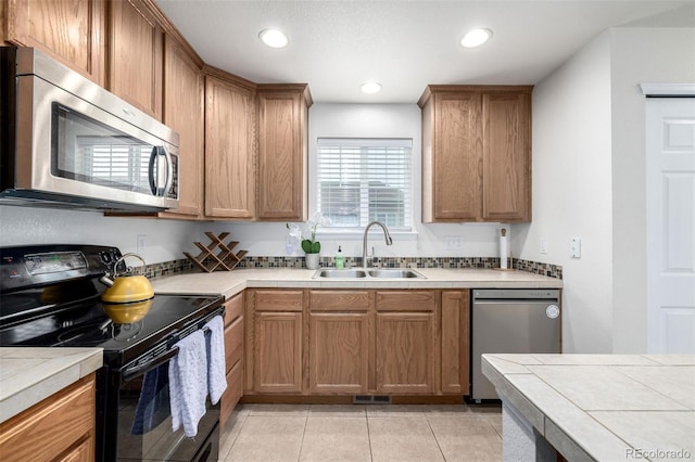 kitchen featuring light tile patterned flooring, appliances with stainless steel finishes, tile counters, and a sink