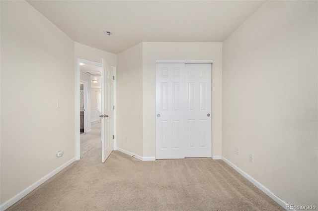 unfurnished bedroom featuring light colored carpet, baseboards, and a closet