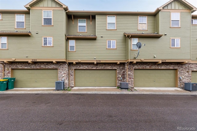back of house featuring central air condition unit, board and batten siding, and an attached garage
