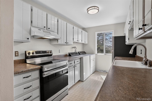 7902 Chase Cir Unit 152, Arvada, CO 80003 - kitchen with stainless steel range with electric stovetop, under cabinet range hood, washing machine and clothes dryer, dark countertops, and white cabinets