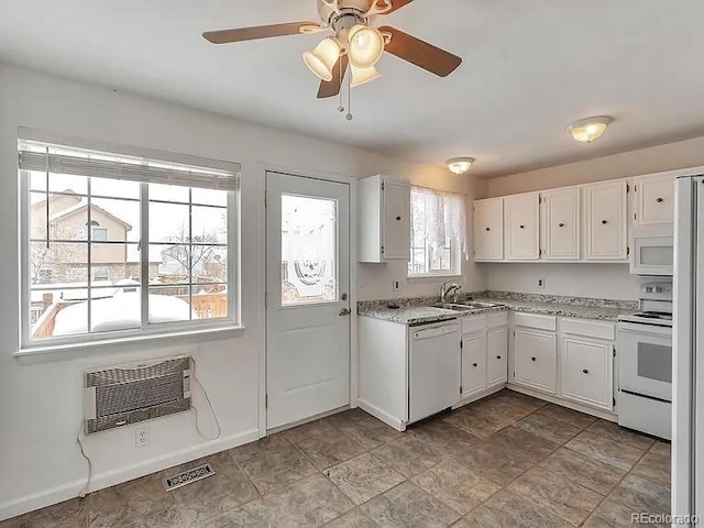 kitchen featuring visible vents, an AC wall unit, a sink, white appliances, and white cabinets