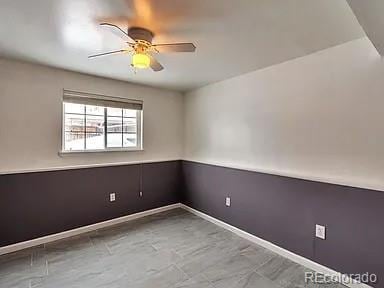 spare room with a ceiling fan and baseboards