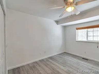 unfurnished room featuring visible vents, wood finished floors, baseboards, and ceiling fan