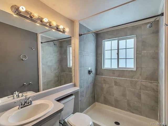 bathroom featuring a tile shower, toilet, and vanity