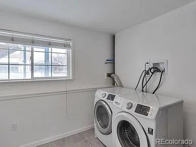 laundry room featuring light wood finished floors, laundry area, baseboards, and separate washer and dryer