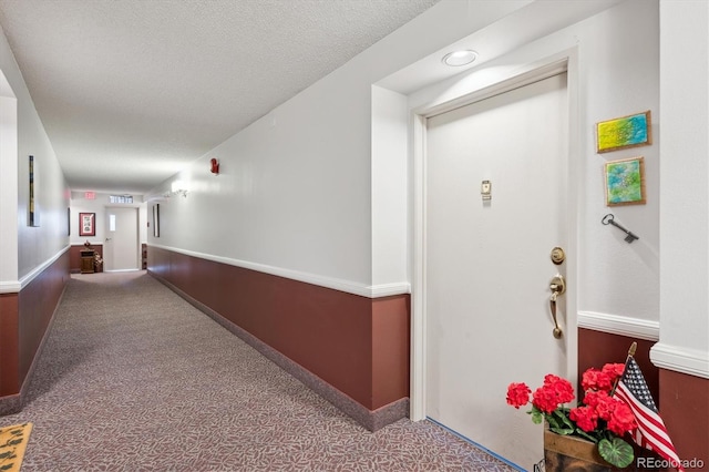hallway featuring carpet flooring and a textured ceiling
