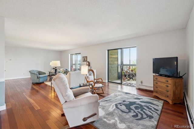 living area featuring baseboard heating, wood finished floors, and a textured ceiling