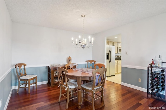dining space with hardwood / wood-style floors, a chandelier, a textured ceiling, and baseboards